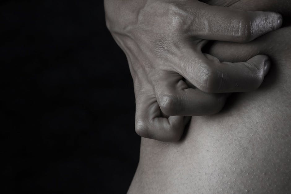 Close-up of a hand gripping skin, emphasizing emotion and tension with a dark, moody backdrop.